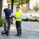 Officer Standing Near The Man On Electric Scooter